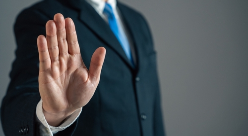 A business man holds up his hand indicating you should check for the hidden limitation of debt consolidation.