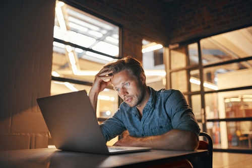 An entrepreneur looks confused as he stares at his laptop trying to understand how reverse consolidation works.